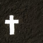 top view of white cross shape with dark soil funeral death grim