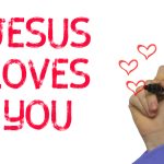 Hand with marker writing word Jesus Loves You